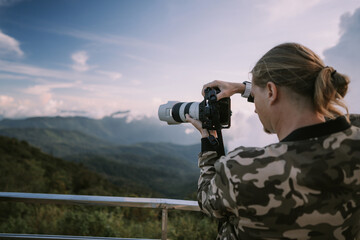 Obraz premium Man photographer shooting sunset at the highest point in Thailand