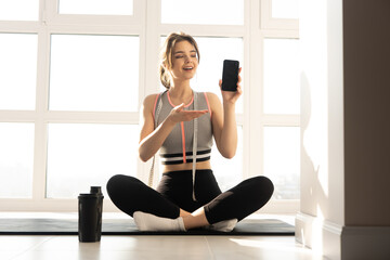 Fototapeta na wymiar Sportswoman showing mobile phone on fitness mat