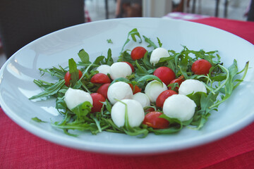 Delicious and easy healthy eating - Italian caprese salad with mozzarella cheese, arugula, cherry tomatoes ans balsamic sauce
