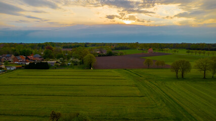 Fototapeta premium Aerial photo of agricultural fields with beautiful sunset with sun rays taken with a drone. High quality photo