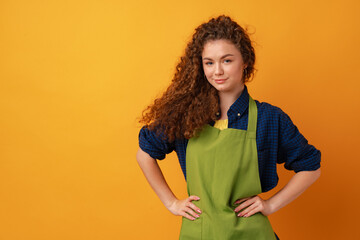 Young woman in a green apron on yellow background