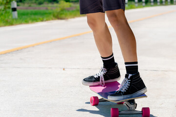 Close Up A young Asian man's legs are skateboarding on a country road on a sunny and clear day., Play surf skate.