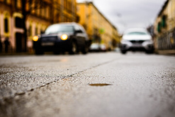 Rainy day in the big city, the approaching car. Close up view from the asphalt level
