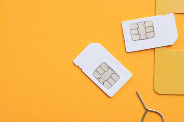 Modern SIM cards and needle on orange background, flat lay. Space for text - obrazy, fototapety, plakaty