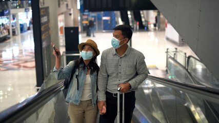 Couple Asian people walking in airport terminal waiting for  flight boarding to travel by air