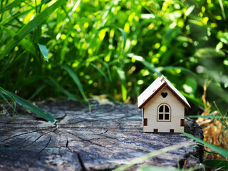 Miniature white toy model house in wooden background near green backdrop. Eco Village, abstract environmental background. Real estate mortgage property insurance dream home ecology concept