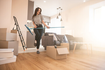 Joyful girl playing on mop like guitar at home