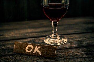 Glass of red wine with the wooden plank on it is an inscription 