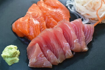 slice raw tuna and salmon fish sashimi Japanese food with radish on plate dipping shoyu  or soybean sauce couple wasabi 