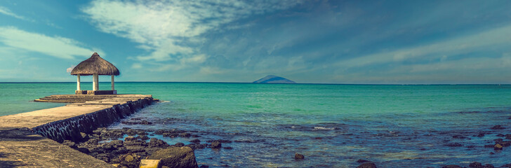 Panoramic view of a beautiful lagoon and a concrete pontoon leading to a hatched kiosk overlooking the sea on the island of Mauritius