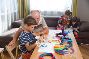 grandparents spend time with their grandchildren at home. Kid boy and his drandfather using 3d...