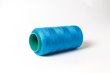 A large bobbin of blue thread on a white background
