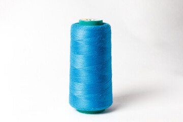 A large bobbin of blue thread on a white background