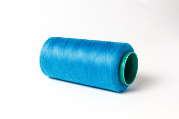 A large bobbin of blue thread on a white background