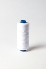 A spool of white thread. White background.