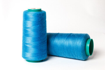 A large bobbin of blue thread on a white background
