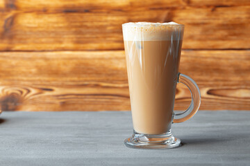 Glass of tasty aromatic latte on wooden background