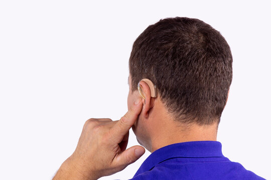 Close up back behind view photo of a senior man tries to set up the hearing aid on the ear to work better.