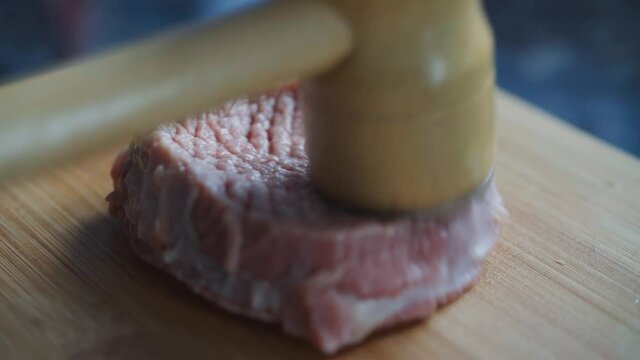 The Woman is beating raw steak with a meat mallet 