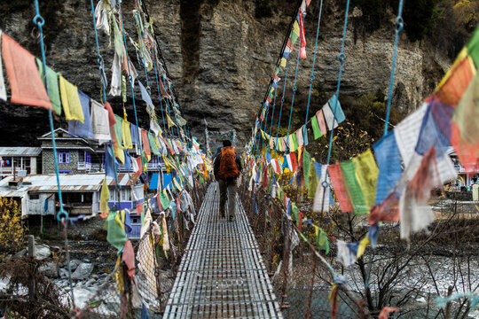 Traveler walking on suspension bridge with Buddhist prayer flags