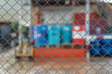 Metal wire fence with blurred background of chemical storage at the factory warehouse, Industrial...