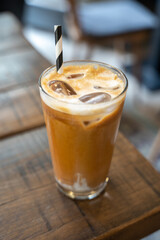 Side view of a ice latte coffee with a straw on a wooden table