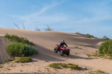 Vibrant sunny day in a desert in Essaouira, Morocco with a quad bike rider driving down a hill © Maximilian Obermaier/Wirestock