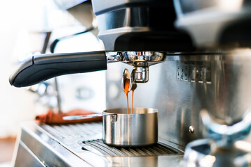 Close-up of espresso pouring from coffee machine into a coffee cup. Professional coffee brewing