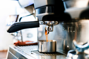 Close-up of espresso pouring from coffee machine into a coffee cup. Professional coffee brewing