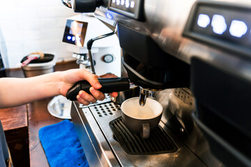 Close-up hand of barista plug the portafilter into coffee machine to make espresso