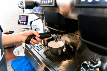 Close-up hand of barista plug the portafilter into coffee machine to make espresso