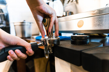 Close-up of barista presses ground coffee using tamper to make espresso