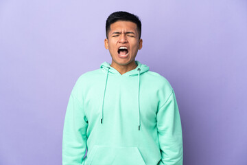 Young Ecuadorian man isolated on purple background shouting to the front with mouth wide open