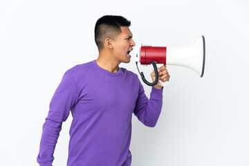 Young Ecuadorian man isolated on white background shouting through a megaphone to announce...