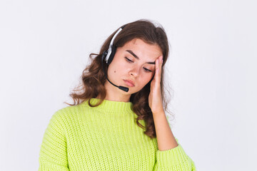 Young beautiful woman with freckles light makeup in sweater on white background with headphones helpline worker call centre manager sad tired bored