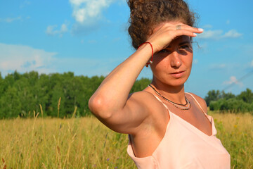 A young girl looks into the distance shielding her eyes from the sun with her hand