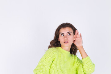 Young beautiful woman with freckles light makeup in sweater on white background gossip talk listen secret