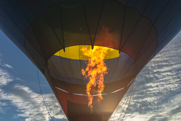 Obraz premium Hot flame from a gas burner light up inside of a hot air balloon at evening.
