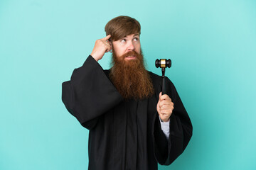 Naklejka premium Redhead caucasian judge man isolated on blue background having doubts and thinking