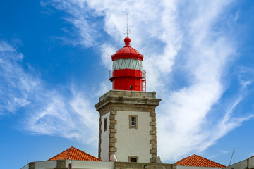 Lighthouse on top of a rock cliff and blue sky with clouds. Lisbon Portugal.