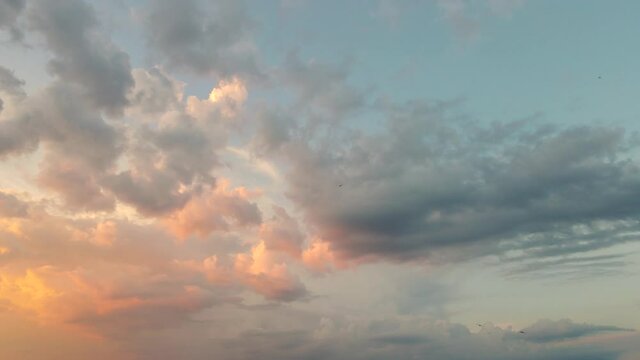 Beautiful orange clouds move in the sunlight against the blue sky. Time lapse, evening sky at sunset. Weather, cloudy nature background, time lapse. Video, footage for transition or intro. UHD 4K.