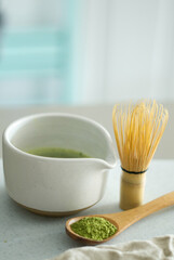 Mixing matcha with wooden spoon and chasen whisk in chawan bowl.