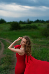 Obraz premium a young girl in a red dress meets the sunset in a green field