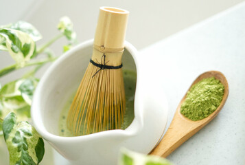 Mixing matcha with wooden spoon and chasen whisk in chawan bowl.