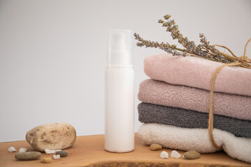cosmetic product on wood.
folded towel and a few dried flower petals.
white background soft composition, relaxing and clean.
Empty label area suitable for mockup