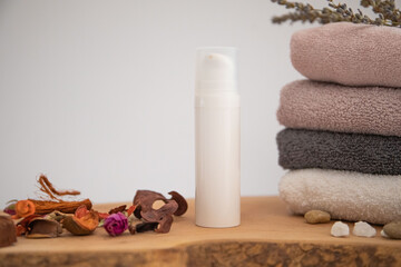 cosmetic product on wood.
folded towel and a few dried flower petals.
white background soft composition, relaxing and clean.
Empty label area suitable for mockup