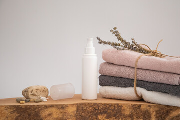cosmetic product on wood.
folded towel and a few dried flower petals.
white background soft composition, relaxing and clean.
Empty label area suitable for mockup
