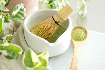Mixing matcha with wooden spoon and chasen whisk in chawan bowl.