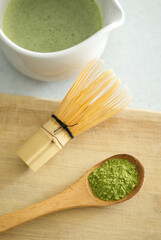 Mixing matcha with wooden spoon and chasen whisk in chawan bowl.