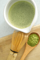 Mixing matcha with wooden spoon and chasen whisk in chawan bowl.